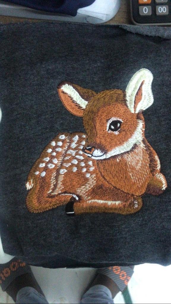 Embroidered fawn on dark fabric