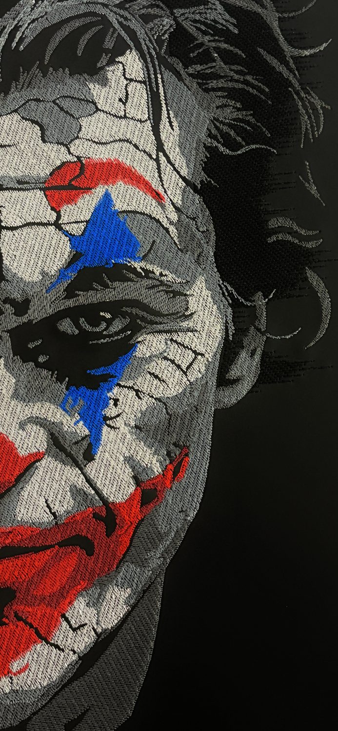 Embroidered Joker portrait artwork in grey, red and blue thread